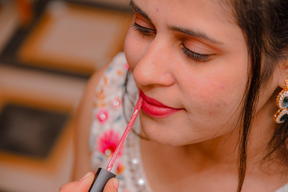 A woman applying bright lipstick with focus on makeup details.