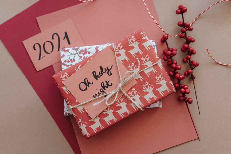 Beautifully wrapped Christmas gift with calligraphy tag 'Oh Holy Night' and red festive decor.