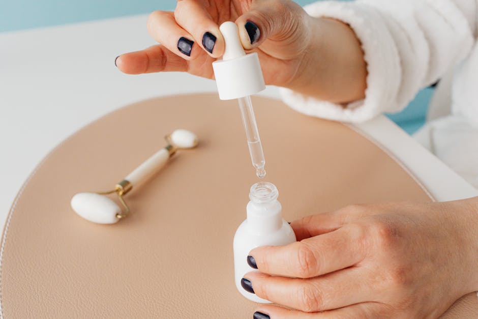 Close-up of hands using serum dropper with jade roller, perfect for skincare routines.