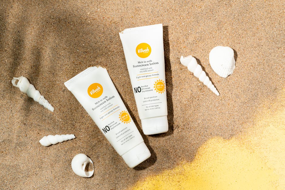 Two sunscreen lotion tubes on sandy beach alongside seashells for sun protection imagery.