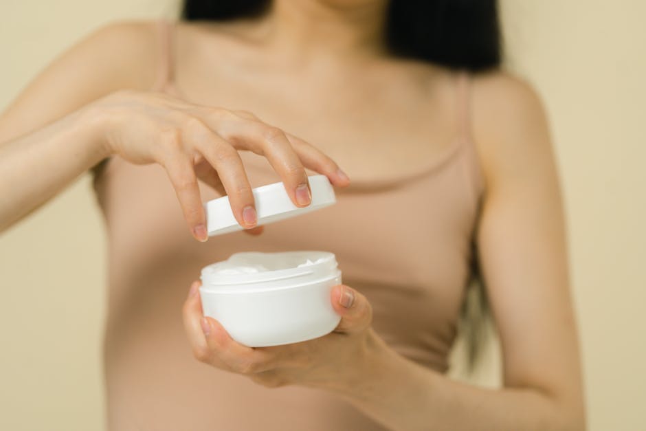 Close-up of a woman opening a cream jar with her hands, in a studio.