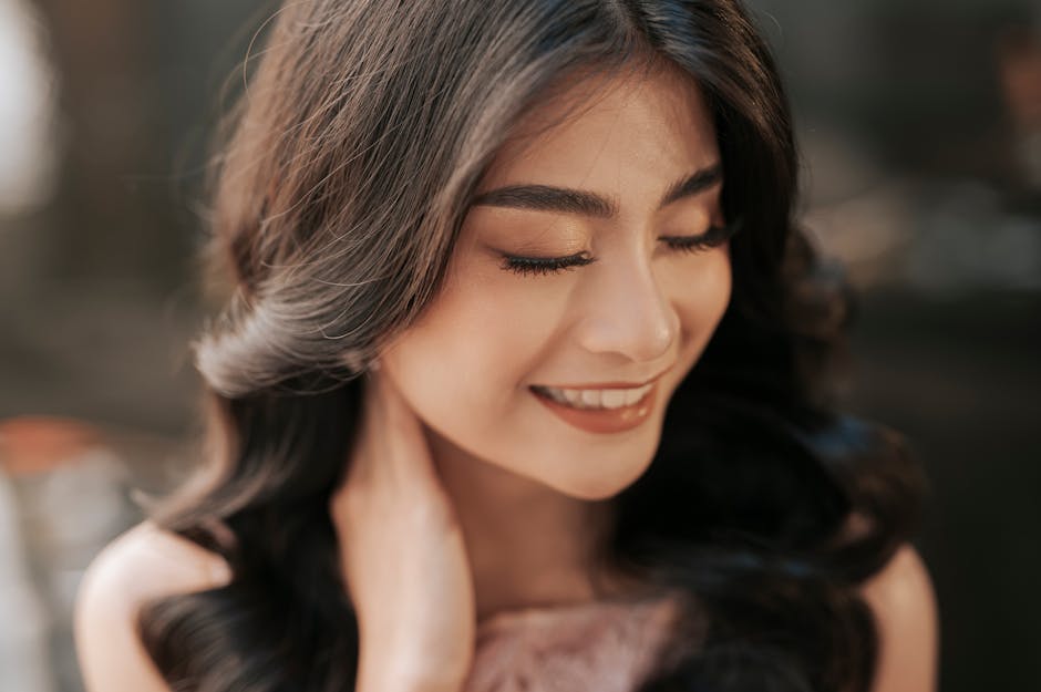 Close-up of a smiling woman with closed eyes, exuding natural elegance and beauty.