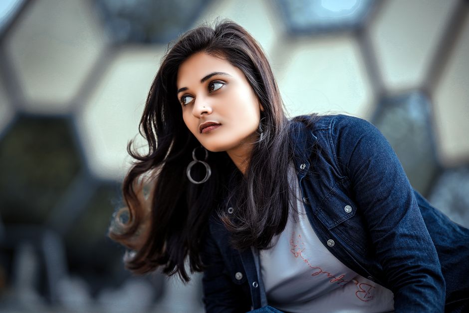 A stylish woman in a denim jacket looking away with a modern architectural background.