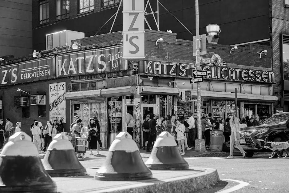 Black and white photo of Katz's Delicatessen in New York with people walking by.