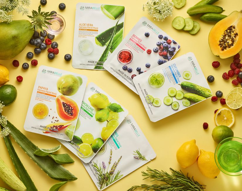 A collection of botanical face masks surrounded by fresh fruits and herbs on a yellow background.