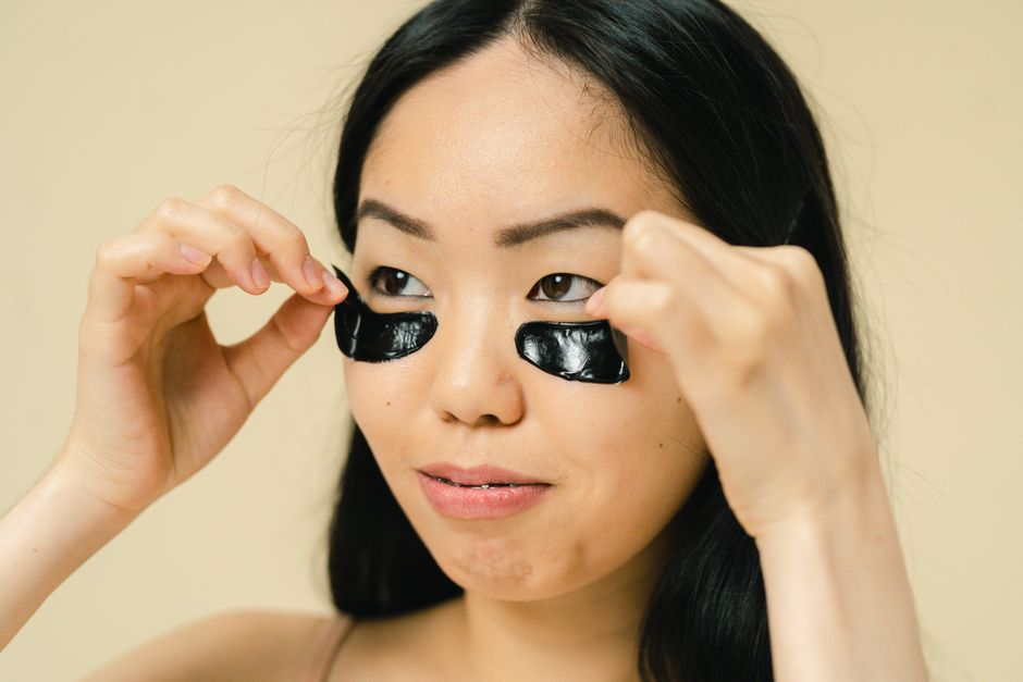 Close-up of a woman placing black eye patches during a skincare routine.