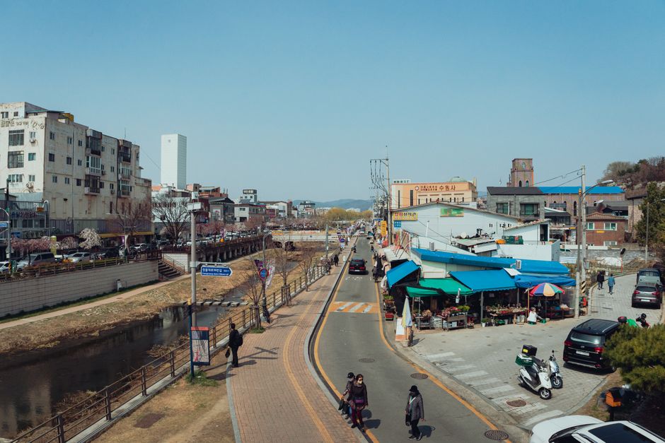 A bustling street scene in Seoul, South Korea showcasing local market life and architecture under a clear sky.