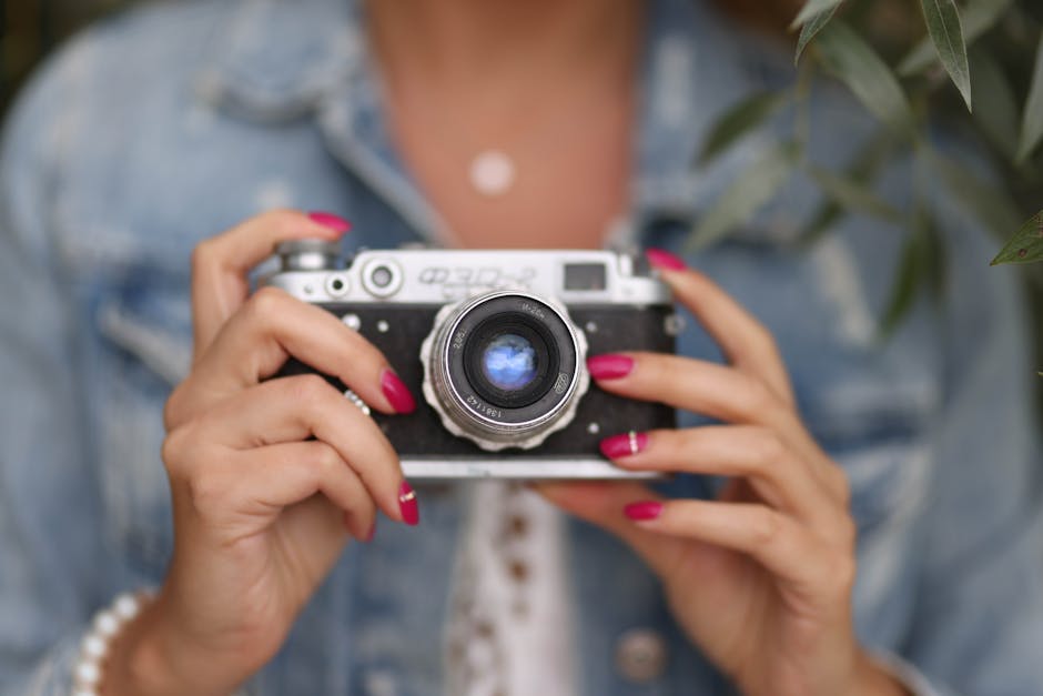 Close-up of a woman holding a vintage camera outdoors, showcasing nostalgia and style.
