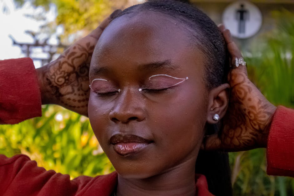 Close-up portrait of a serene woman with intricate henna, eyes closed outdoors.