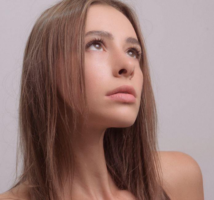 Close-up portrait of a young woman gazing upward, serene and thoughtful.