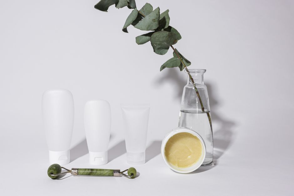 Elegant studio shot of skincare products with jade roller and vase, ideal for beauty and wellness themes.
