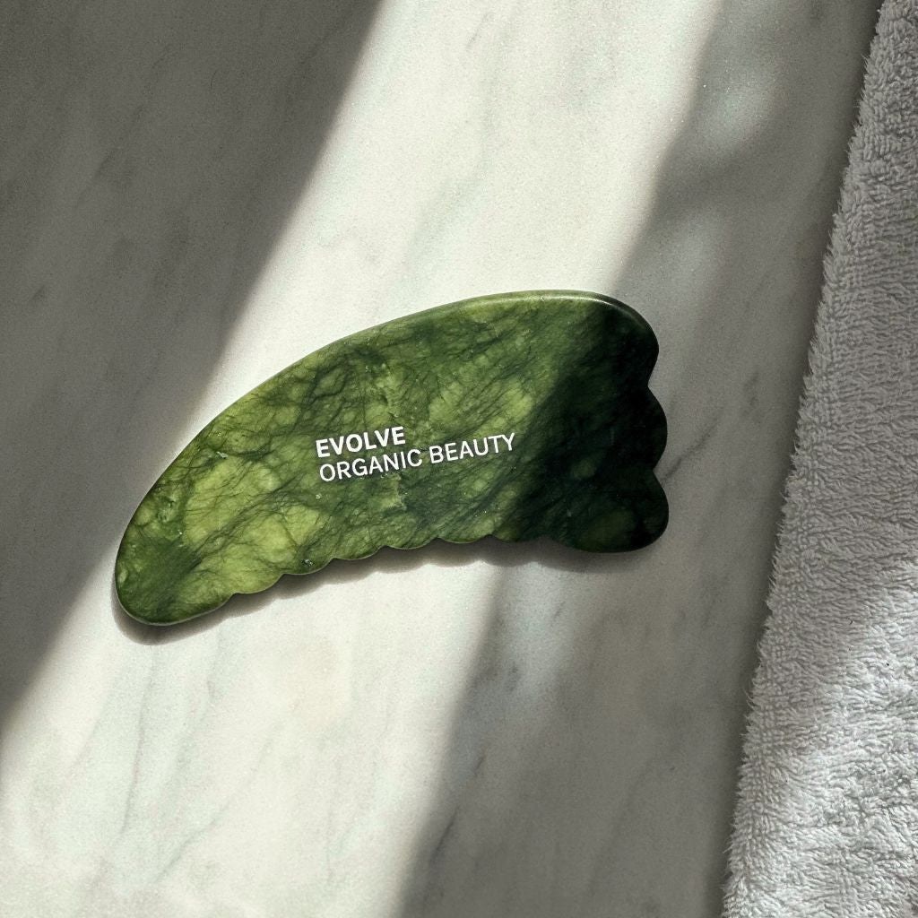 Green Evolve Jade Body Gua Sha resting on a towel